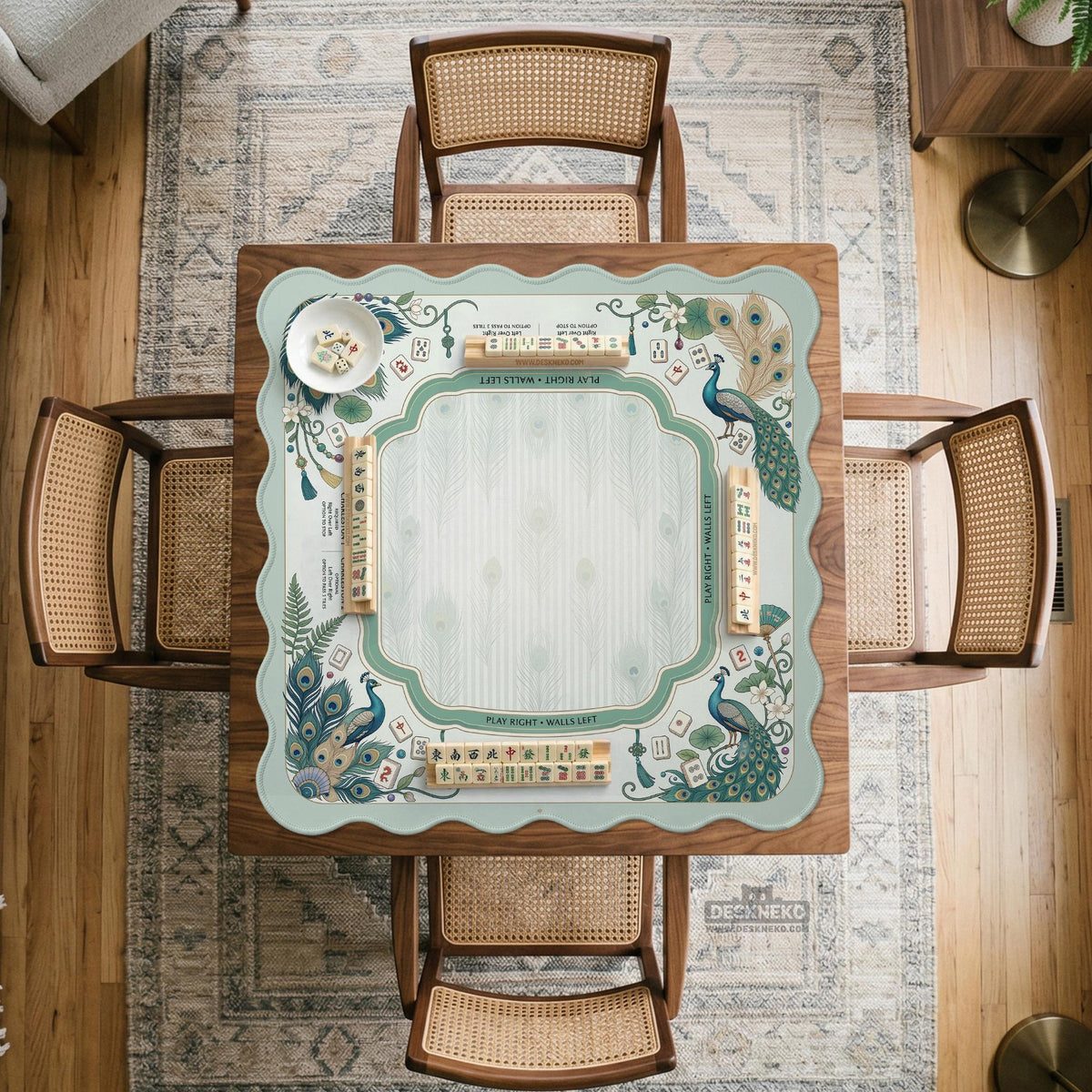 Teal square mahjong mat with peacock feathers, soft floral pattern, tassel details, and printed rule guide text in the center.