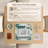 Teal square mahjong mat with peacock feathers, soft floral pattern, tassel details, and printed rule guide text in the center.