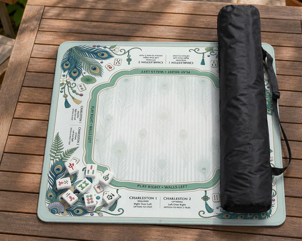 Teal square mahjong mat with peacock feathers, soft floral pattern, tassel details, and printed rule guide text in the center.