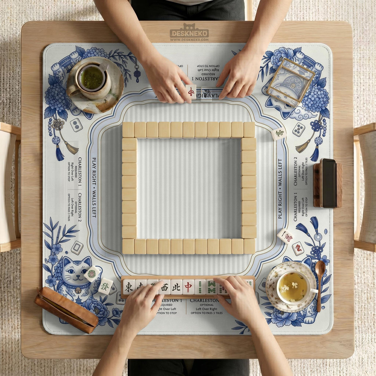 Blue and white square mahjong mat with lucky cat artwork, floral chinoiserie pattern, tile icons, and a rule guide layout.