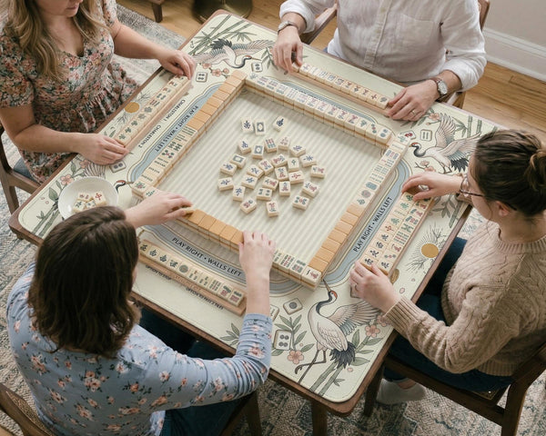 Beige square mahjong mat with a sage border, crane birds, bamboo, flowers, tile icons, and printed rules around a clean center play area.