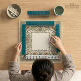 Square mahjong table mat with vintage bird artwork, floral border detail, and sage green, cream, muted blue, and terracotta tones.