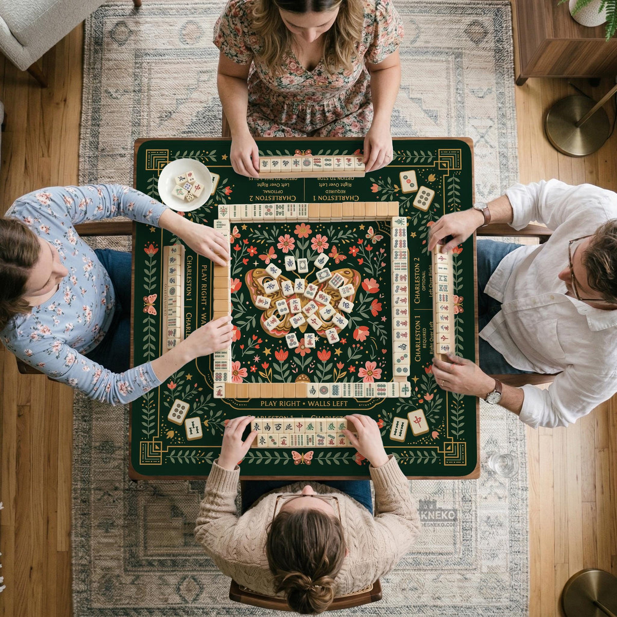 Dark botanical mahjong table mat with a floral border, large moth and butterfly design in the center, gold corner frame, and printed rules layout around the edge.