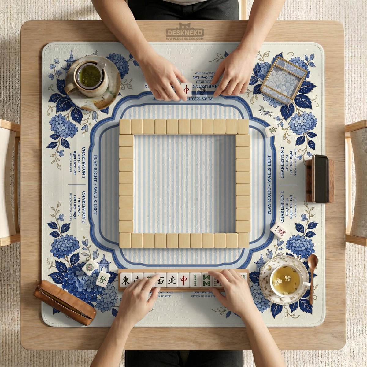 Blue and white mahjong table mat with a floral border, small birds, pagoda details, striped center, and printed rules around the edge.