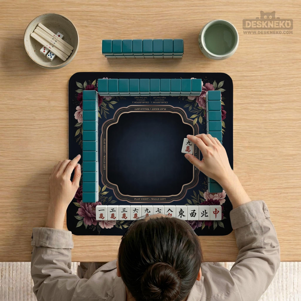 Burgundy mahjong mat with a floral border, gold botanical details, and printed American Mahjong rules on a dark background.