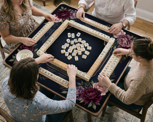 Burgundy mahjong mat with a floral border, gold botanical details, and printed American Mahjong rules on a dark background.