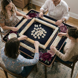 Burgundy mahjong mat with a floral border, gold botanical details, and printed American Mahjong rules on a dark background.