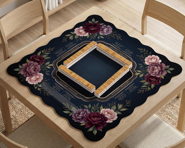Burgundy mahjong mat with a floral border, gold botanical details, and printed American Mahjong rules on a dark background.