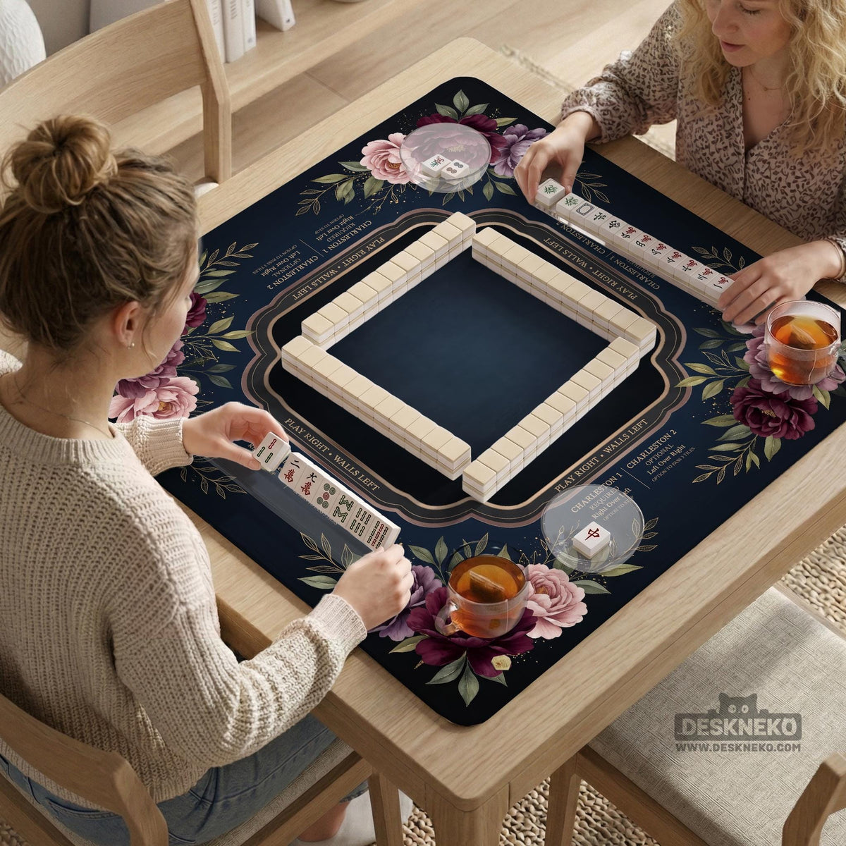 Burgundy mahjong mat with a floral border, gold botanical details, and printed American Mahjong rules on a dark background.