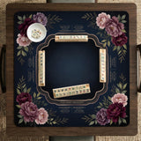 Burgundy mahjong mat with a floral border, gold botanical details, and printed American Mahjong rules on a dark background.