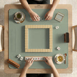 A square sage green mahjong mat with scalloped edges on a plain background.