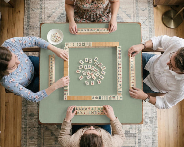 A square sage green mahjong mat with scalloped edges on a plain background.