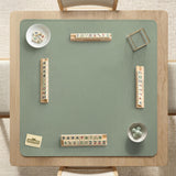 A square sage green mahjong mat with scalloped edges on a plain background.