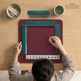 Plain burgundy square mahjong mat with scalloped edges on a white background.