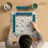 Pink floral mahjong table mat with peonies, blue hydrangeas, sage green leaves, and an ivory background.