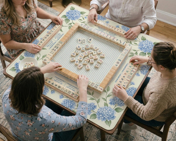 A square mahjong mat with blue hydrangea flowers, green vines, a cream background, a striped center, and printed rules around the border.