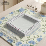 A square mahjong mat with blue hydrangea flowers, green vines, a cream background, a striped center, and printed rules around the border.