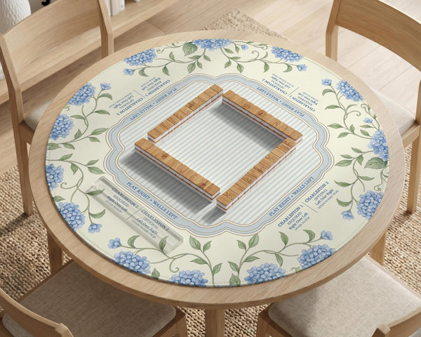 A square mahjong mat with blue hydrangea flowers, green vines, a cream background, a striped center, and printed rules around the border.