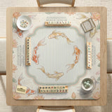 Sage and cream mahjong mat with a koi fish pond pattern, lotus blooms, water ripples, and printed instructions around the border. One version has a scalloped edge.