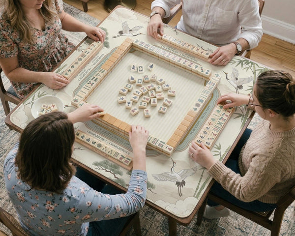Sage green scalloped mahjong mat with bamboo, crane, and blossom illustration and printed rules around the border.