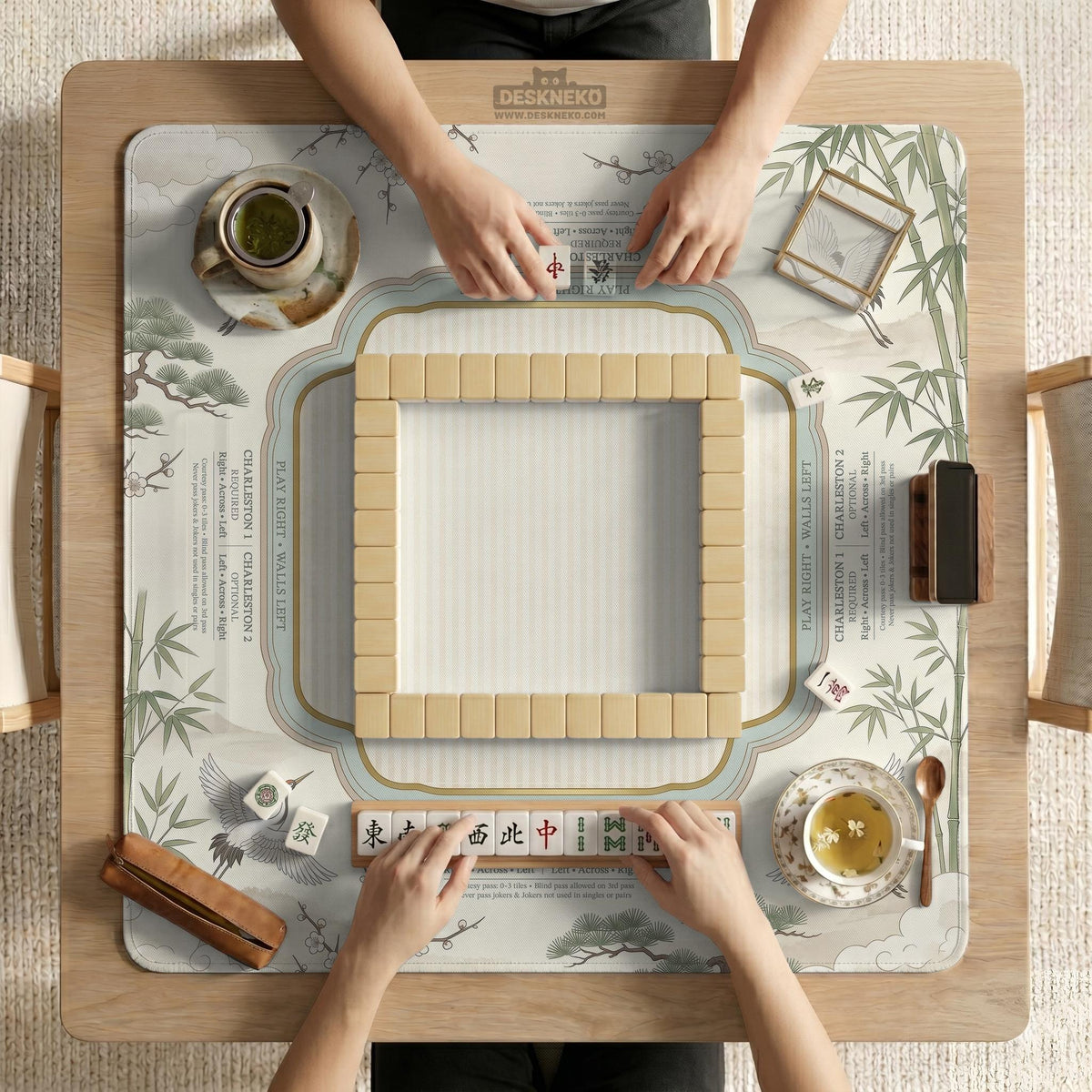 Sage green scalloped mahjong mat with bamboo, crane, and blossom illustration and printed rules around the border.