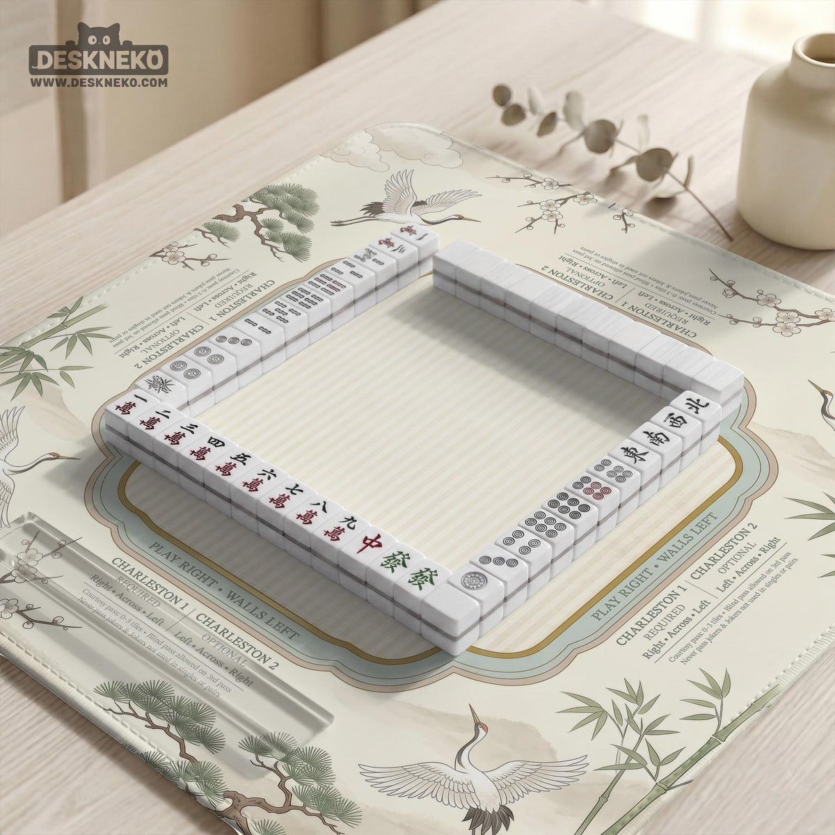 Sage green scalloped mahjong mat with bamboo, crane, and blossom illustration and printed rules around the border.