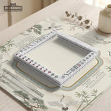 Sage green scalloped mahjong mat with bamboo, crane, and blossom illustration and printed rules around the border.