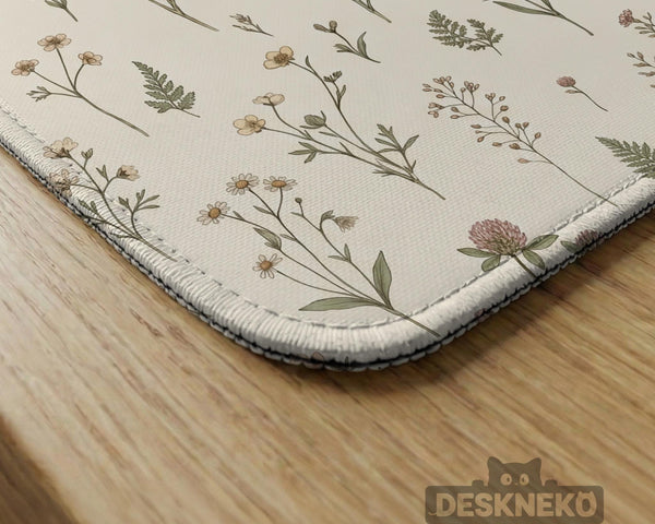 Cream mahjong mat with a floral pattern of small wildflowers and sage leaves, shown with a scalloped edge on a light neutral background.