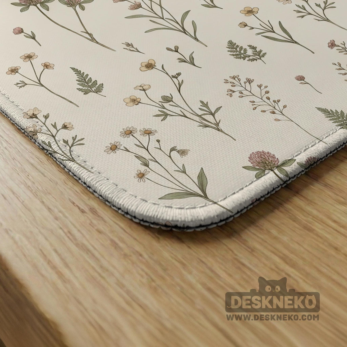 Cream mahjong mat with a floral pattern of small wildflowers and sage leaves, shown with a scalloped edge on a light neutral background.