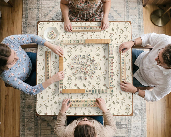 Cream mahjong mat with a floral pattern of small wildflowers and sage leaves, shown with a scalloped edge on a light neutral background.