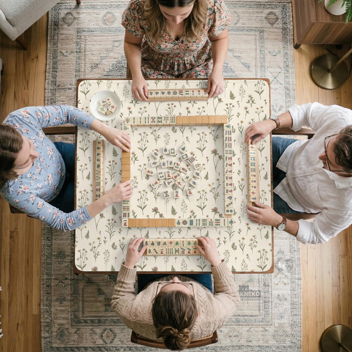 Cream mahjong mat with a floral pattern of small wildflowers and sage leaves, shown with a scalloped edge on a light neutral background.