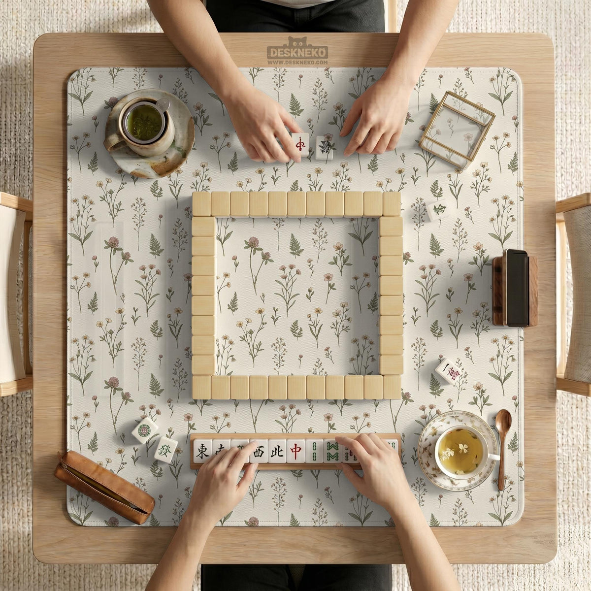 Cream mahjong mat with a floral pattern of small wildflowers and sage leaves, shown with a scalloped edge on a light neutral background.