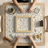 Cream mahjong mat with a floral pattern of small wildflowers and sage leaves, shown with a scalloped edge on a light neutral background.