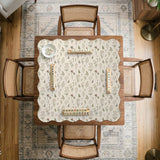 Cream mahjong mat with a floral pattern of small wildflowers and sage leaves, shown with a scalloped edge on a light neutral background.