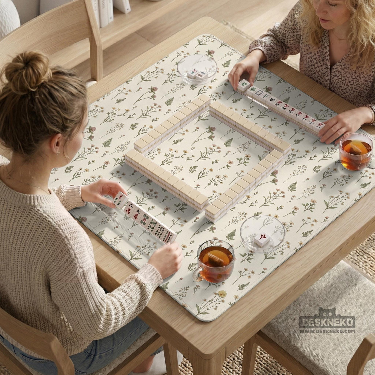 Cream mahjong mat with a floral pattern of small wildflowers and sage leaves, shown with a scalloped edge on a light neutral background.