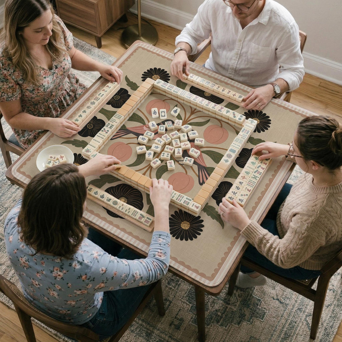Beige mahjong mat with a botanical floral bird design, blush flowers, olive green leaves, black flower accents, and a warm linen-style background. Scalloped edge option shown.