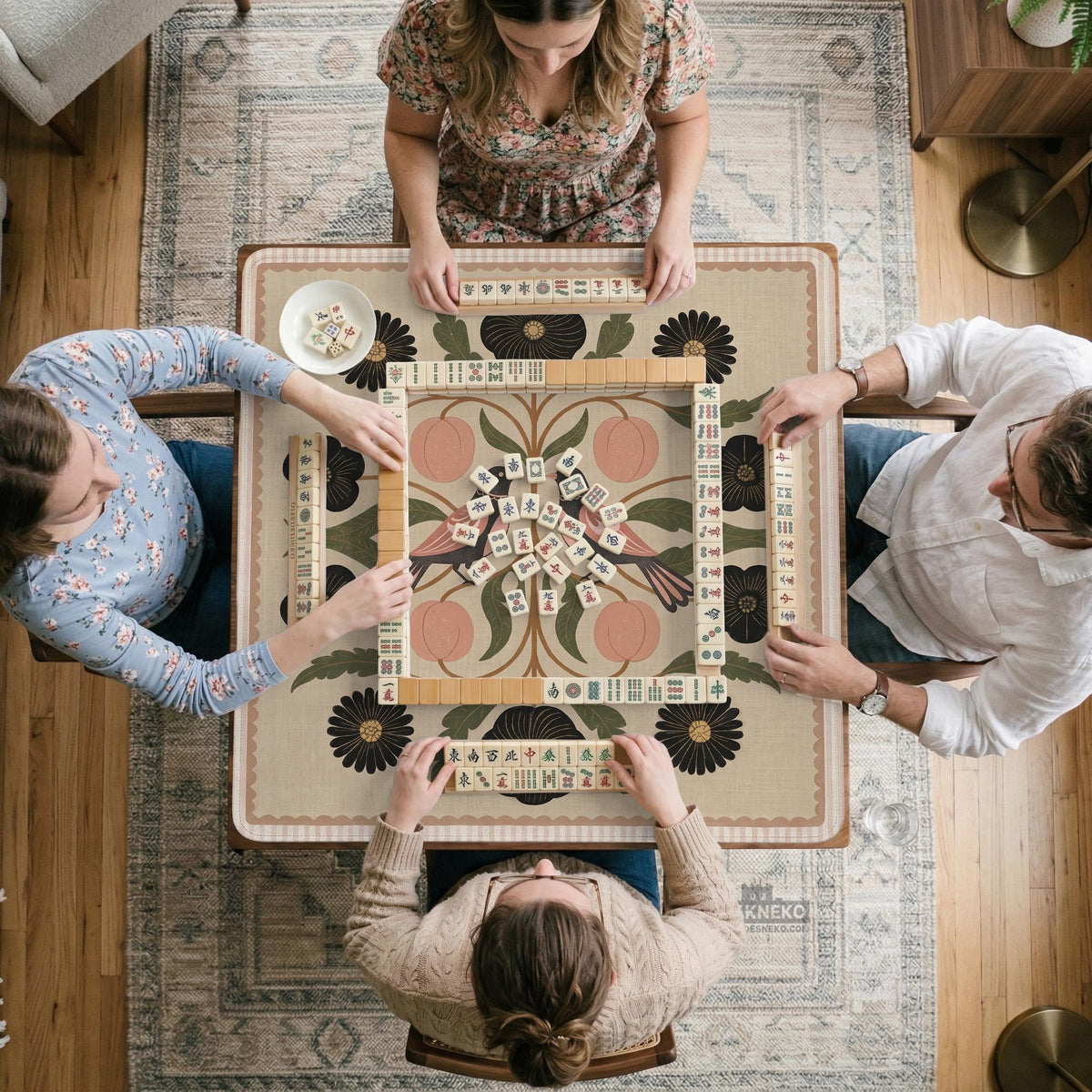 Beige mahjong mat with a botanical floral bird design, blush flowers, olive green leaves, black flower accents, and a warm linen-style background. Scalloped edge option shown.