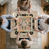 Beige mahjong mat with a botanical floral bird design, blush flowers, olive green leaves, black flower accents, and a warm linen-style background. Scalloped edge option shown.