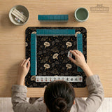 Black square mahjong mat with moths, moonflowers, crescent moons, and scattered stars in a celestial floral pattern.