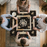 Black square mahjong mat with moths, moonflowers, crescent moons, and scattered stars in a celestial floral pattern.
