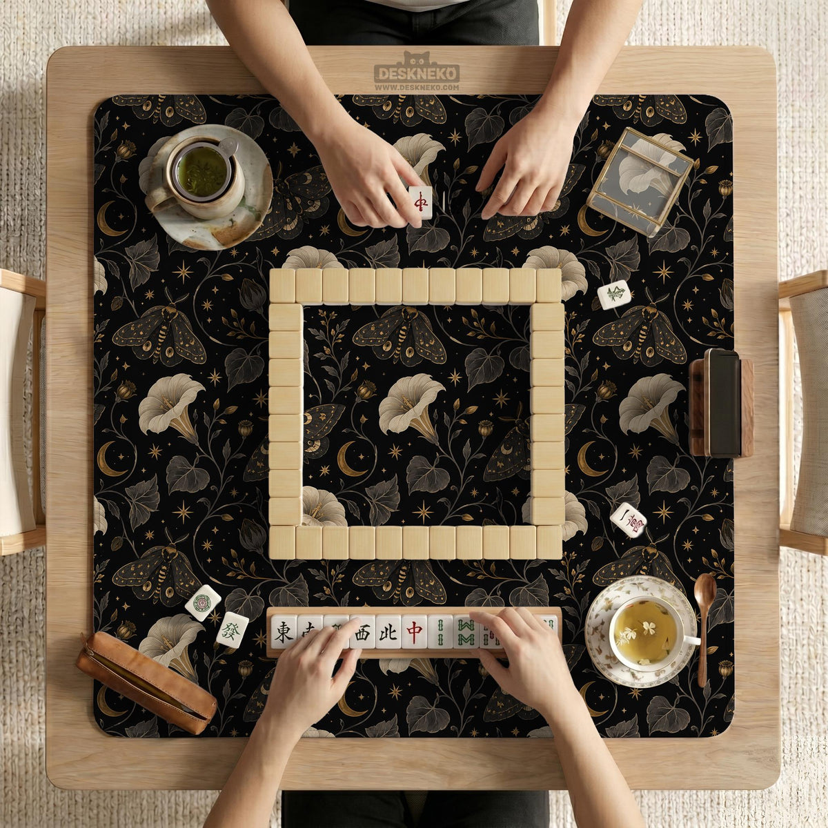 Black square mahjong mat with moths, moonflowers, crescent moons, and scattered stars in a celestial floral pattern.