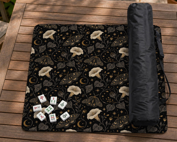 Black square mahjong mat with moths, moonflowers, crescent moons, and scattered stars in a celestial floral pattern.