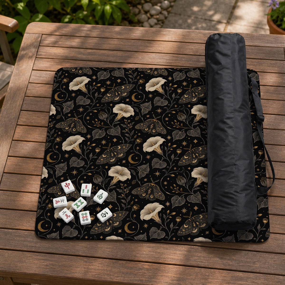 Black square mahjong mat with moths, moonflowers, crescent moons, and scattered stars in a celestial floral pattern.