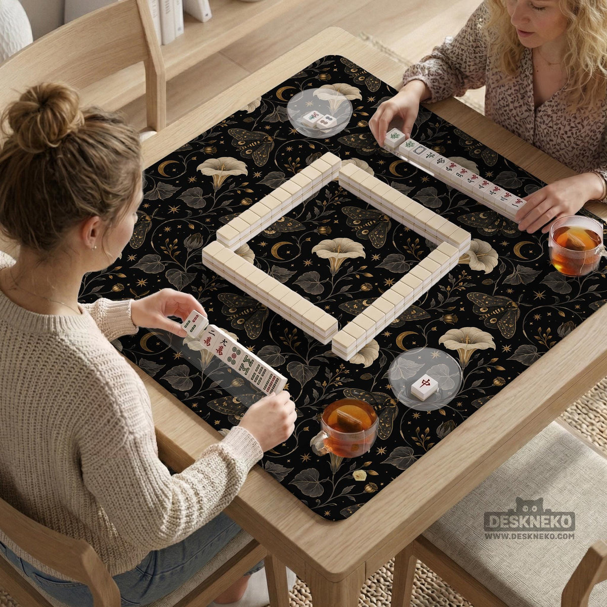 Black square mahjong mat with moths, moonflowers, crescent moons, and scattered stars in a celestial floral pattern.