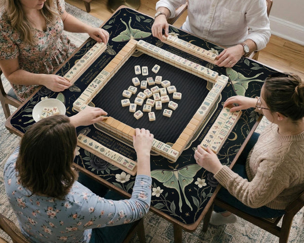 A dark floral mahjong mat with a scalloped edge, moth and flower artwork, and an American Mahjong rules layout on a dark background.