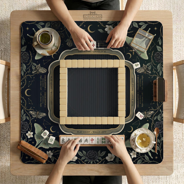 A dark floral mahjong mat with a scalloped edge, moth and flower artwork, and an American Mahjong rules layout on a dark background.