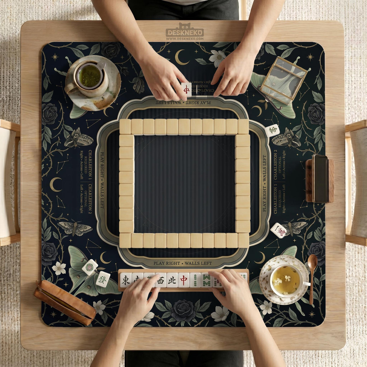 A dark floral mahjong mat with a scalloped edge, moth and flower artwork, and an American Mahjong rules layout on a dark background.