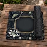 A dark floral mahjong mat with a scalloped edge, moth and flower artwork, and an American Mahjong rules layout on a dark background.