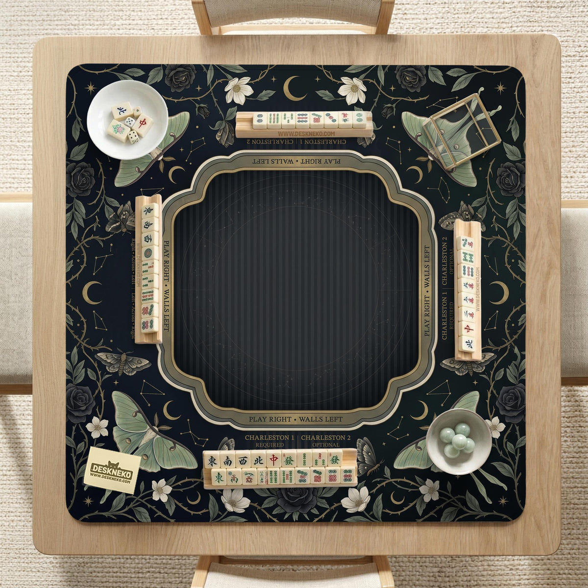 A dark floral mahjong mat with a scalloped edge, moth and flower artwork, and an American Mahjong rules layout on a dark background.