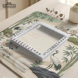 Square mahjong mat with a cream background, sage green cranes, bamboo leaves, peony branches, stones, and thin linework.